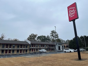 Un hotel Red Roof Inn con un edificio de dos pisos, un estacionamiento y una zona verde.