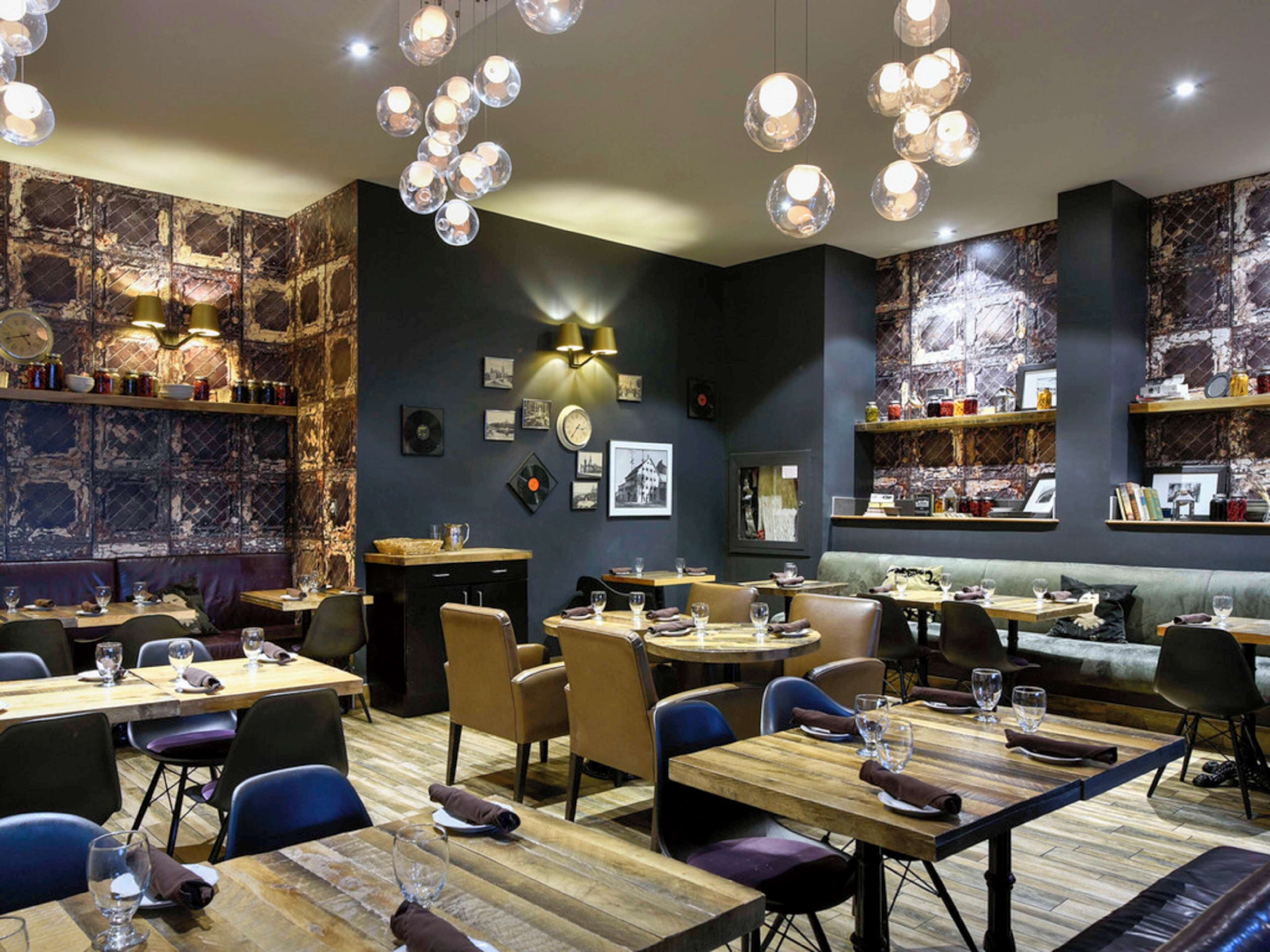 A restaurant interior with wooden tables, chairs, and hanging spherical light fixtures.
