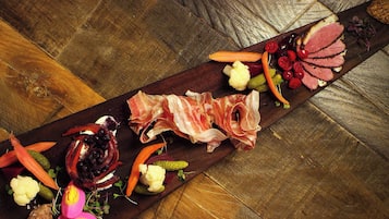 Una tabla de embutidos con diferentes carnes, quesos y verduras.