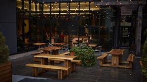 An outdoor seating area with wooden tables and benches, surrounded by glass windows and a sign reading "The Albion Rooms". - DoubleTree by Hilton Ottawa Downtown (Ottawa)
