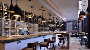 A modern bar area with wooden shelves, black pendant lights, and bar stools. - DoubleTree by Hilton Ottawa Downtown (Ottawa)