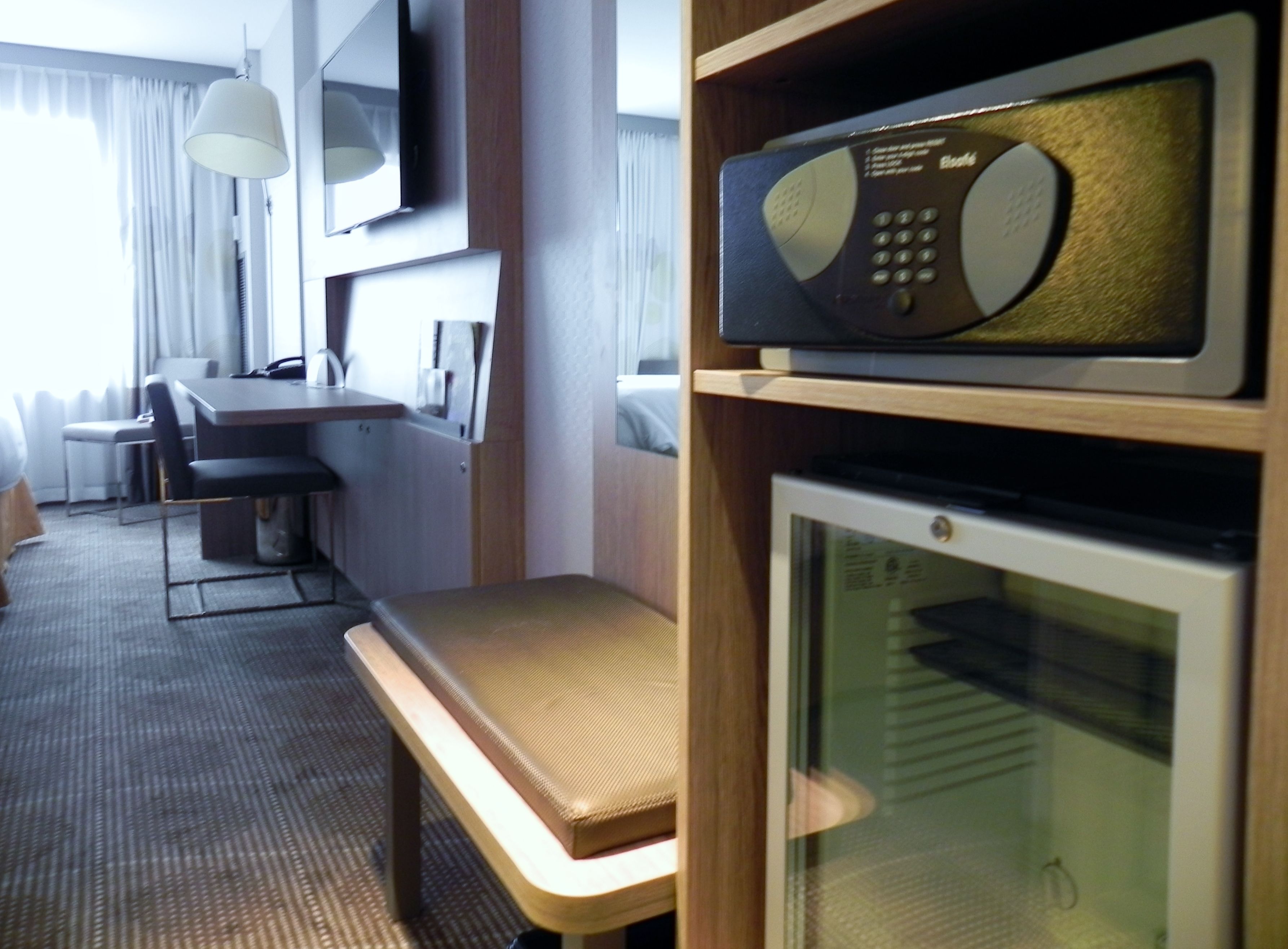 A hotel room with a dining table, chairs, a microwave, and a television.