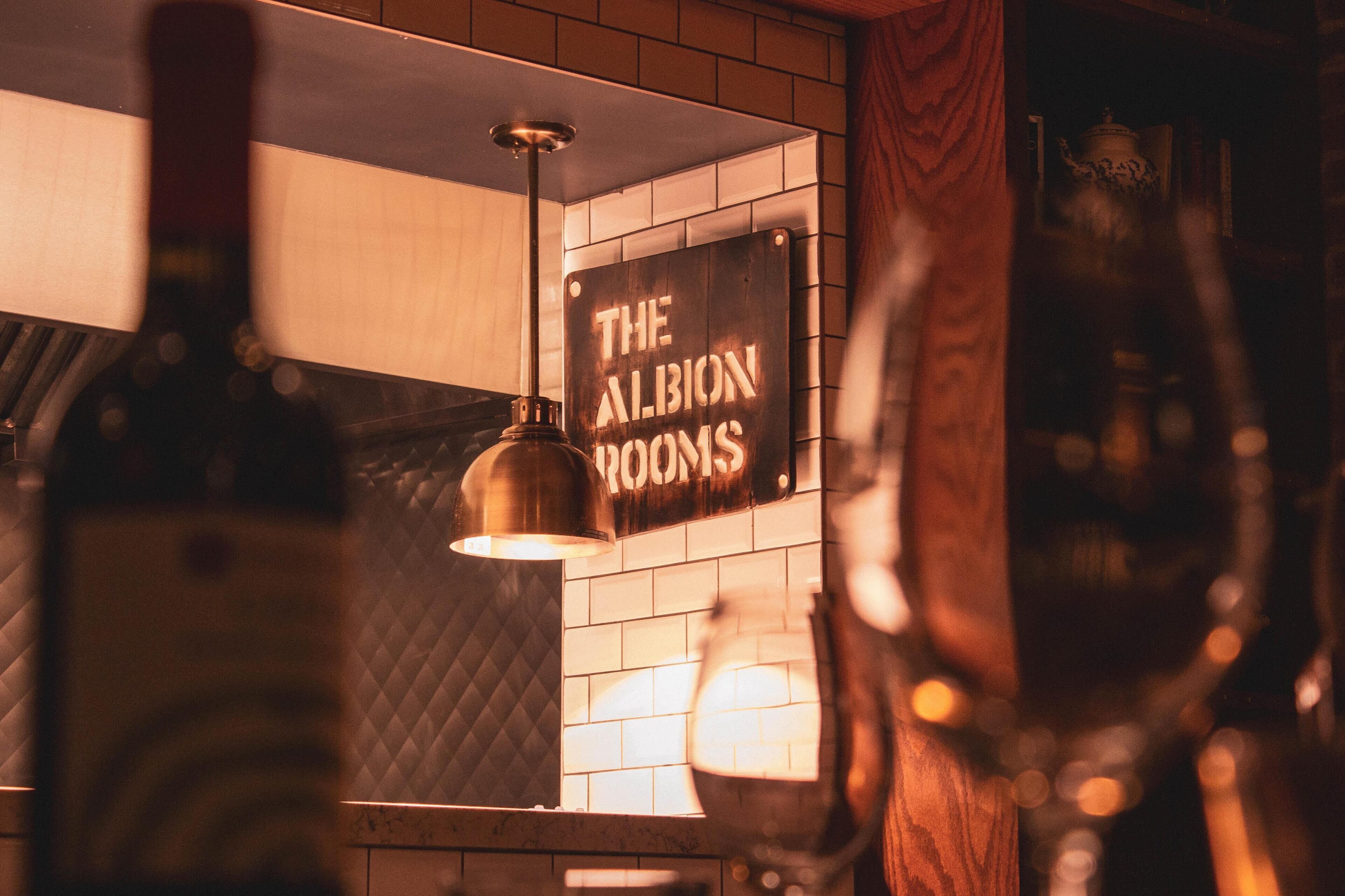 Ein Schild mit der Aufschrift 'THE ALBION ROOMS' in einem Zimmer mit gefliesten Wänden und einer Hängelampe.