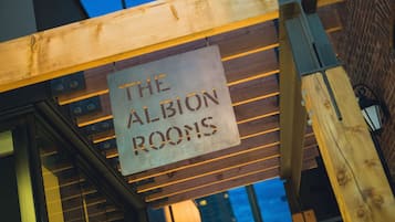 A sign for 'The Albion Rooms' in a building with wooden beams and a brick wall.