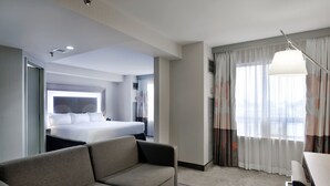 A hotel room with a bed, a sofa, a coffee table, and a large window with curtains. - DoubleTree by Hilton Ottawa Downtown (Ottawa)