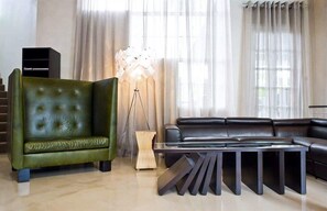 Una sala de estar moderna con un sofá verde, un sofá de cuero negro y una mesa de centro original.