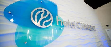 Segnaletica di un hotel con un logo stilizzato e la scritta 'hotel CURREN'.