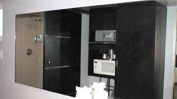 A modern bathroom with a shower, a microwave, and a sink.