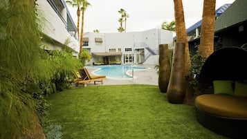 Relax by the pool surrounded by lush greenery and palm trees.