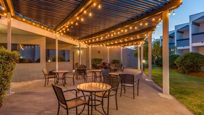 An outdoor patio area with multiple tables and chairs, string lights, and a covered section with a pergola. - Best Western Plus Wine Country Inn & Suites (Santa Rosa)