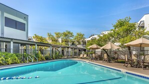 A swimming pool with lounge chairs and umbrellas, surrounded by a fence and greenery. - Best Western Plus Wine Country Inn & Suites (Santa Rosa)