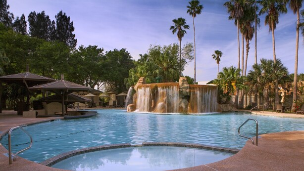A pool area with a no-diving sign, a waterfall feature, and palm trees. - Rancho Viejo Resort and Country Club (Olmito)