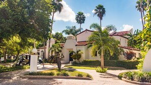 A courtyard with palm trees, a statue, and a building with a tiled roof. - Rancho Viejo Resort and Country Club (Olmito)