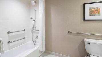 Un baño con bañera, ducha, inodoro y barras de apoyo.