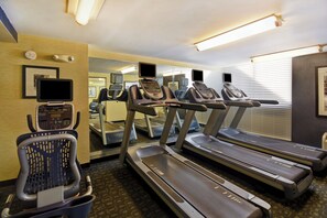 A hotel fitness room with treadmills, a stationary bike, and a mirrored wall.