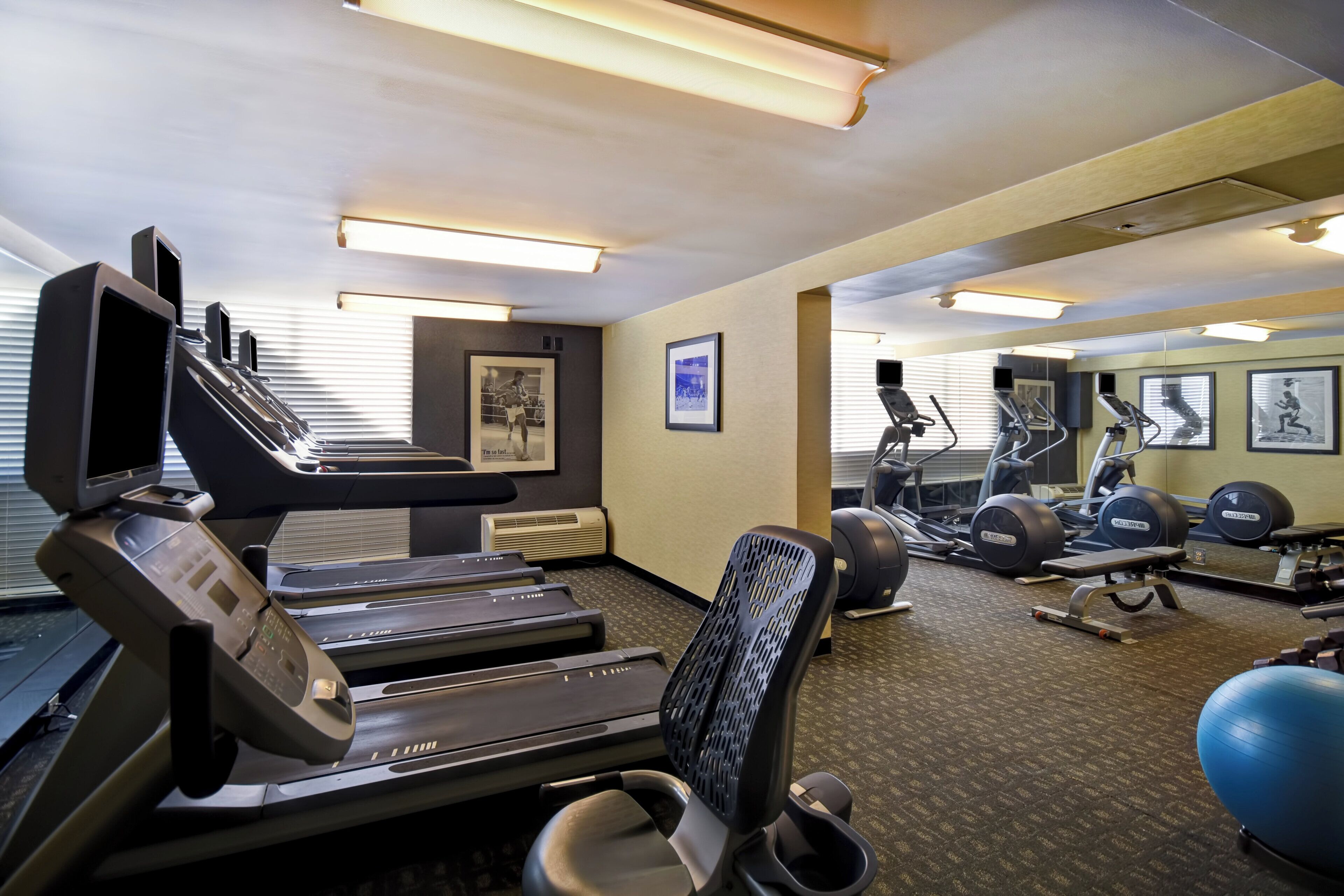 Une salle de sport équipée de tapis de course, de vélos d’exercice et d’un appareil d’aviron.