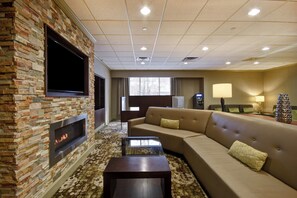 A modern living room with a stone fireplace, a flat-screen TV, a sofa, and a coffee table.