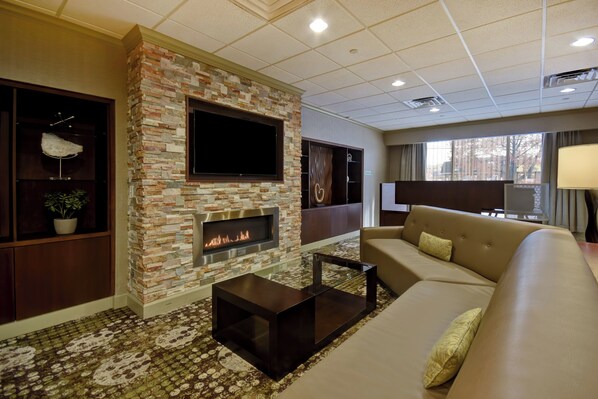 A modern living room with a stone fireplace, a flat-screen TV, a sofa, and a coffee table.