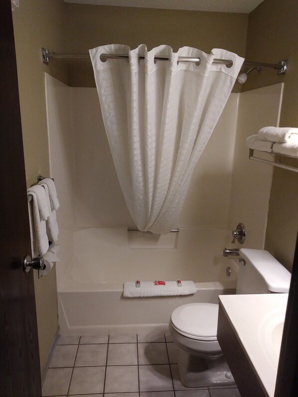 Un baño con bañera, inodoro y cortina de ducha.
