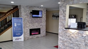 Una zona de recepción con chimenea, un televisor montado y una alfombra roja que lleva a la entrada.