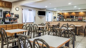 Un restaurante con varias mesas y sillas, una máquina de café y un televisor colgado en la pared.