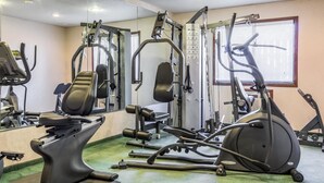 Un gimnasio con diversos equipos de ejercicio, como cintas de correr, elípticas y máquinas de pesas.