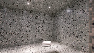 Bathroom features a unique mosaic tile design and a convenient bench with a fresh towel.