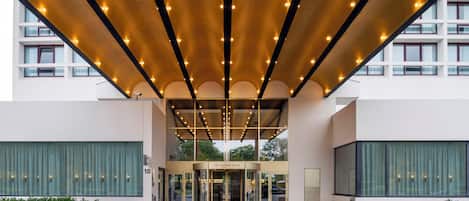 A hotel entrance with a covered entrance, a revolving door, and a sign reading "Crown Plaza".