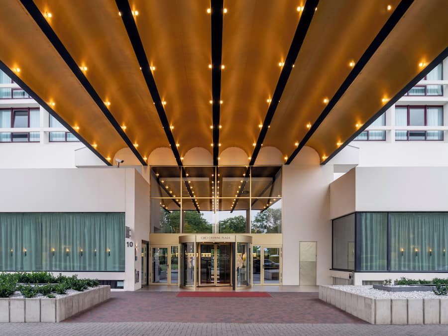 A hotel entrance with a covered entrance, a revolving door, and a sign reading "Crown Plaza".