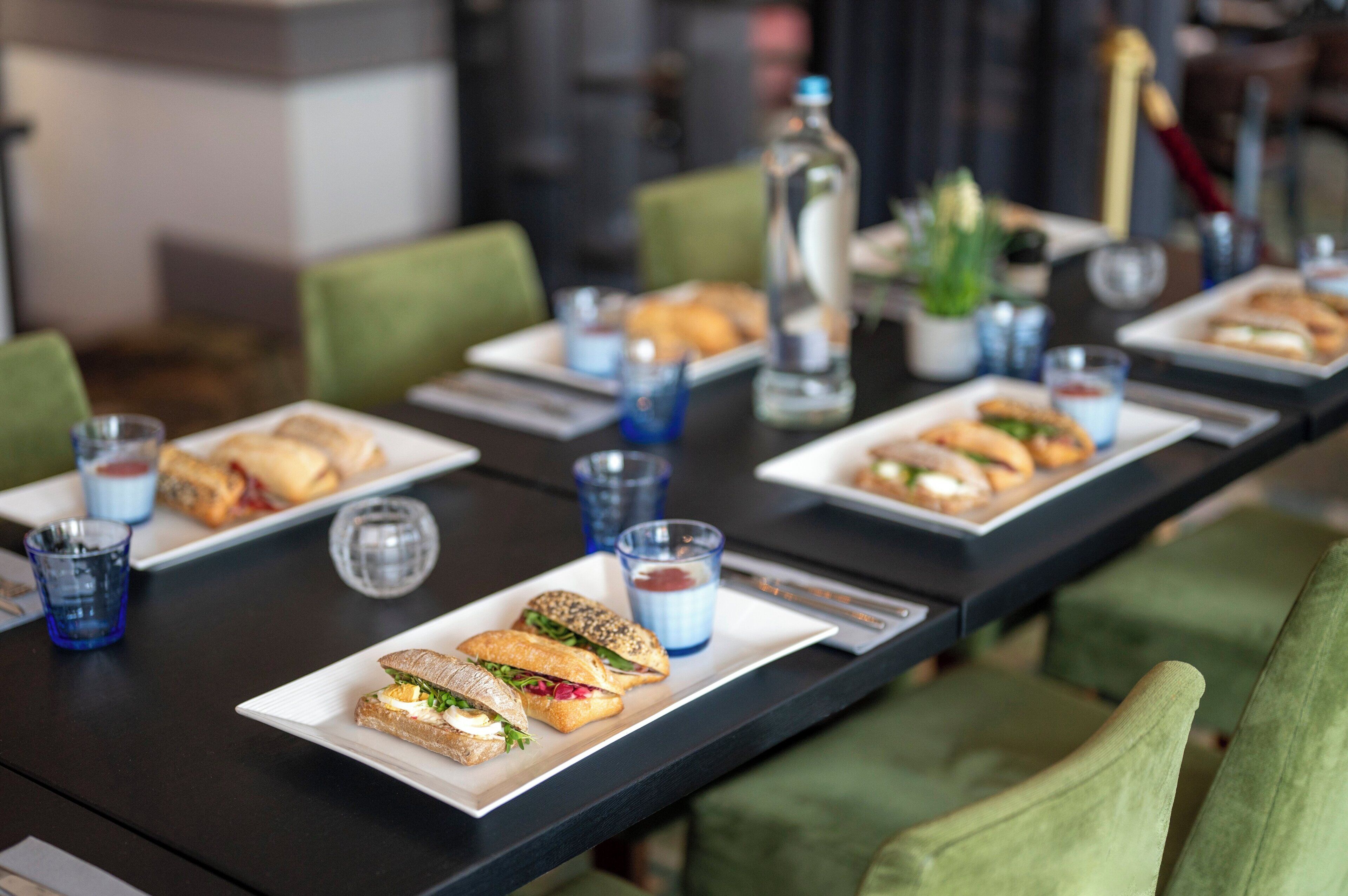 Een eettafel met belegde broodjes en glazen water.