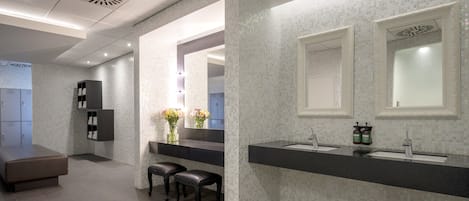 Une salle de bain moderne avec un grand miroir, deux lavabos et un banc.