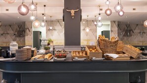 A buffet counter with various food items, a central bull skull decoration, and hanging pendant lights. - Crowne Plaza Antwerp by IHG (Antwerp)