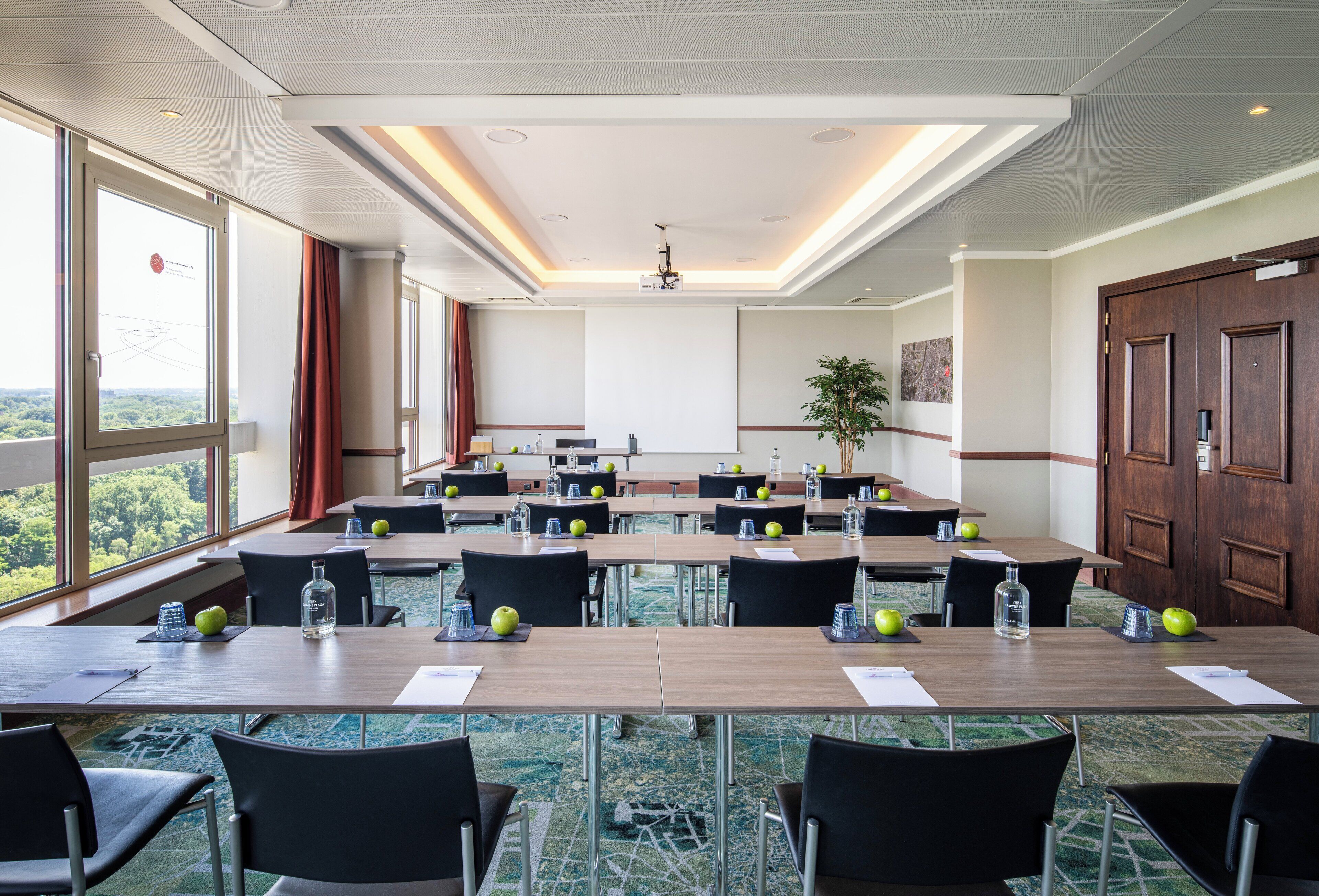 A conference room with multiple tables, chairs, and a large window offering a view of the outdoors.