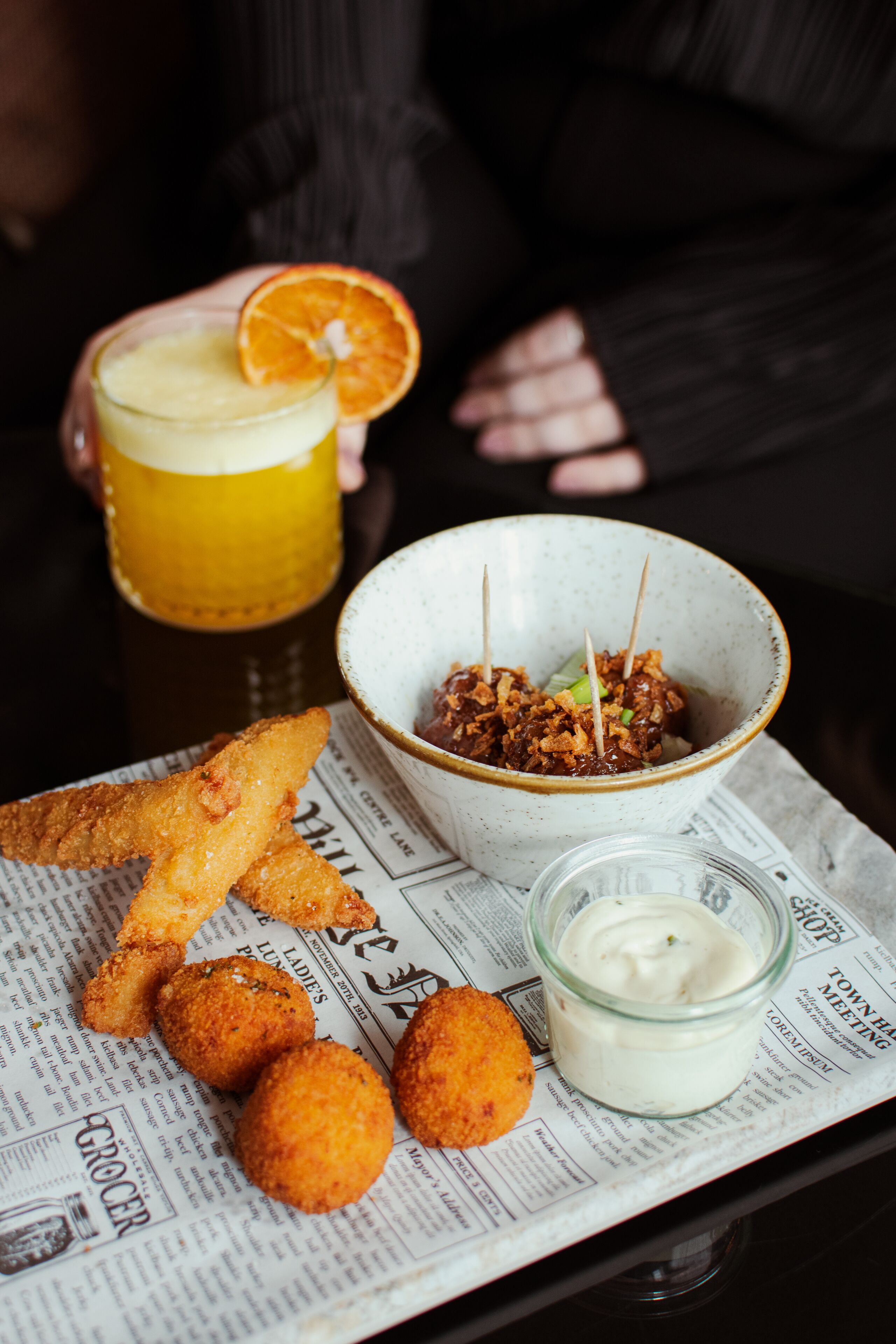 A tray with food items including breaded chicken, a bowl of salad, and a glass of beer.
