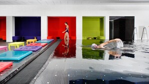 An indoor swimming pool with colorful lanes and a person swimming. - Crowne Plaza Antwerp by IHG (Antwerp)