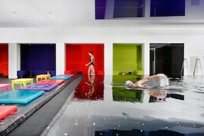An indoor swimming pool with colorful lanes and a person swimming. - Crowne Plaza Antwerp by IHG (Antwerp)
