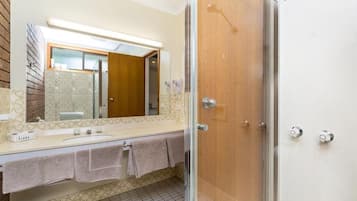 A bathroom with a glass shower enclosure, a sink with a mirror, and a towel rack.