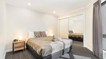 Una habitación de hotel con una cama grande, una mesita de noche, un espejo y una puerta corredera.