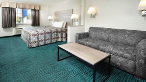 Habitación de hotel con cama, sofá, una mesita y dos lámparas de pared.