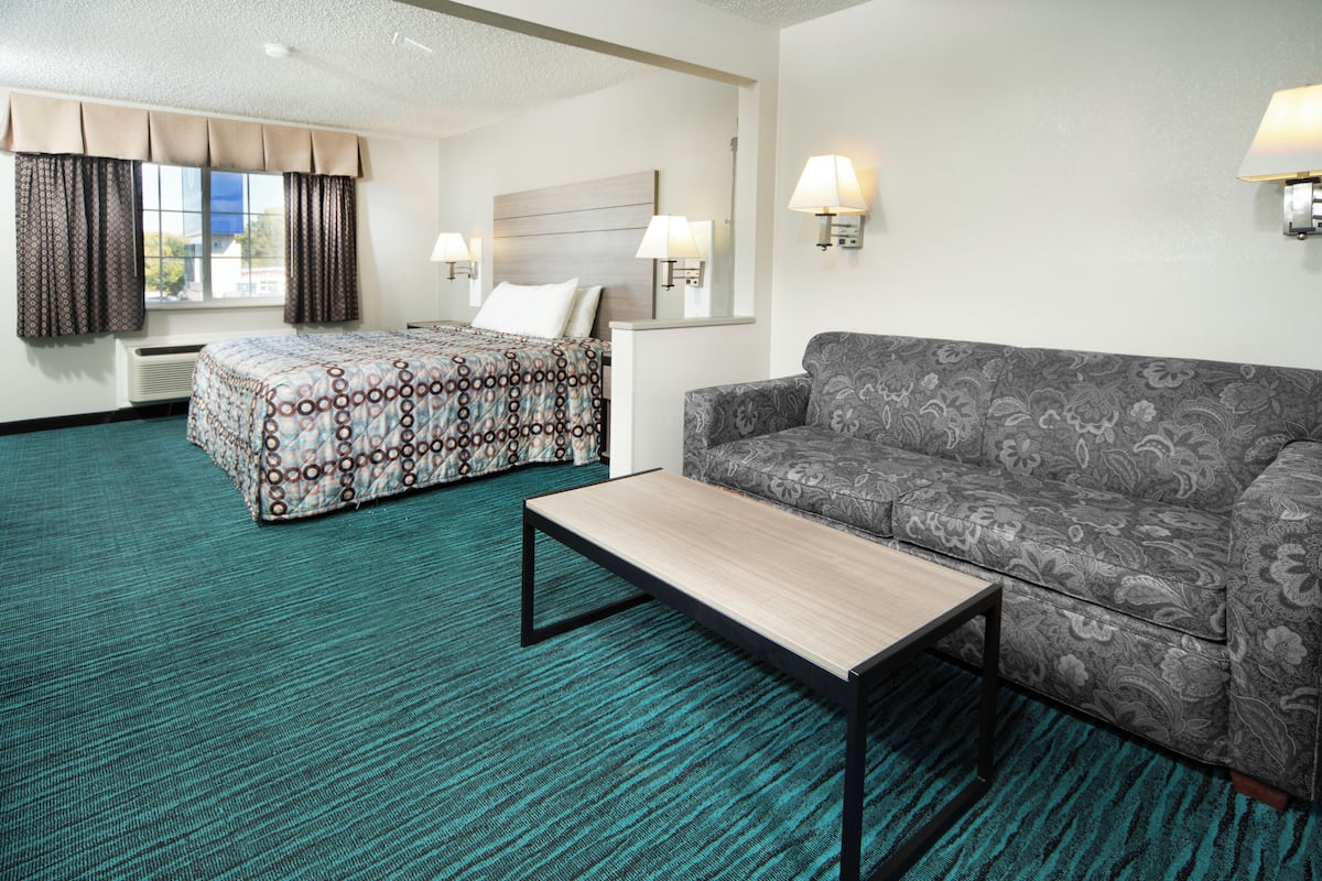 Ein Hotelzimmer mit einem Bett, einer Couch, einem kleinen Tisch und zwei Wandleuchten.