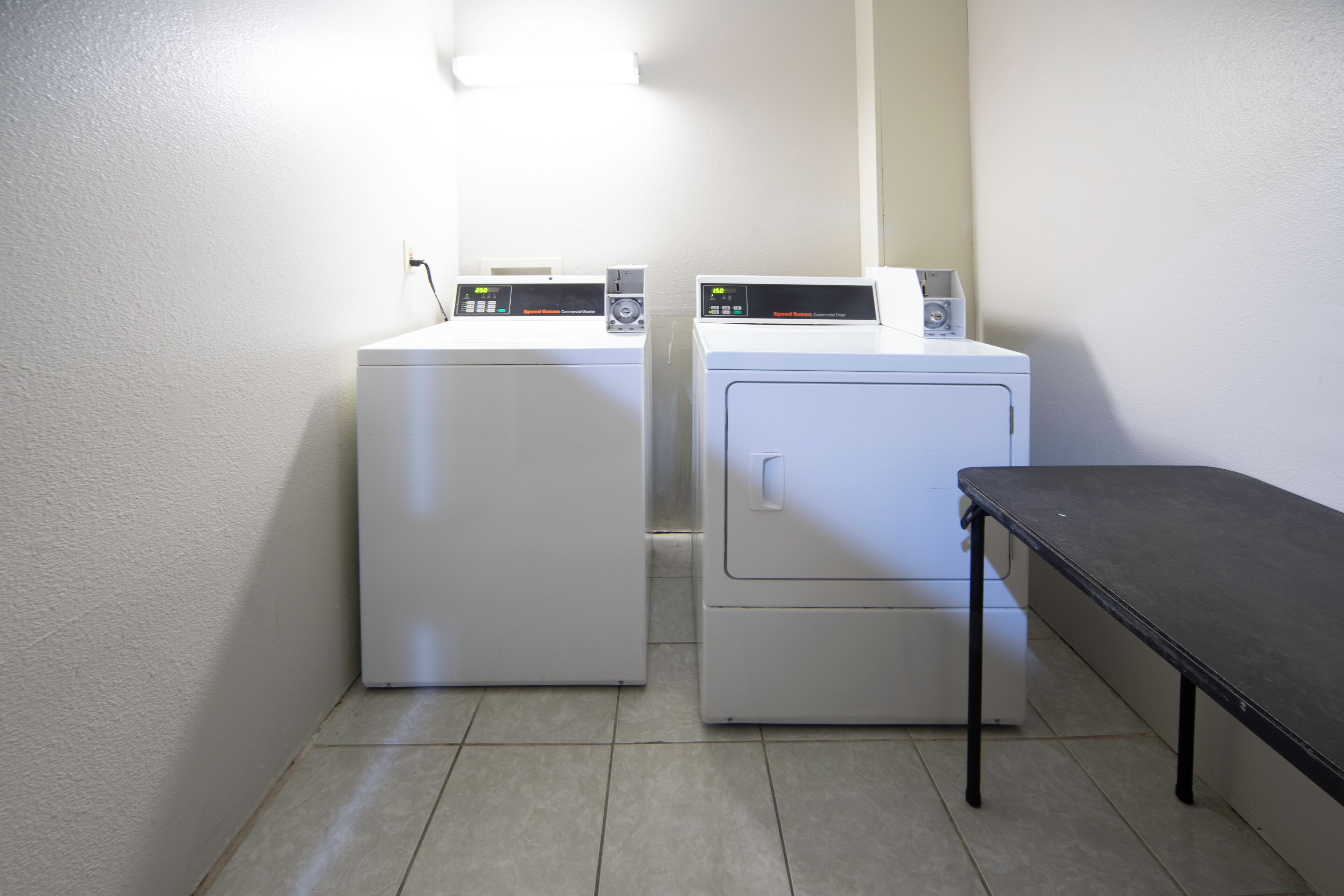A laundry area with two white washing machines and a small table.
