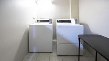 A laundry area with two white washing machines and a small table.