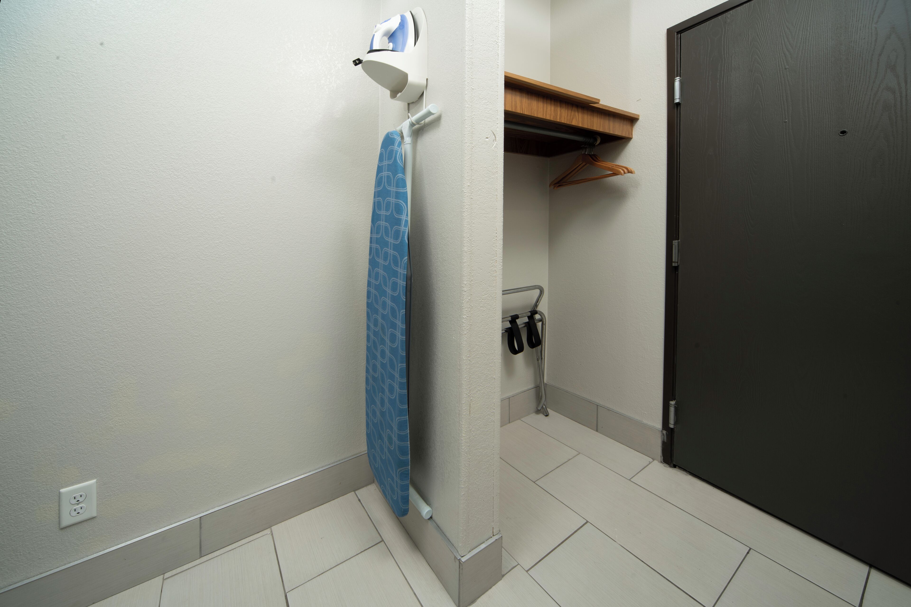 Une salle de bain équipée d’un porte-serviettes, d’une serviette, d’une douche, d’une porte et d’une étagère avec des cintres.