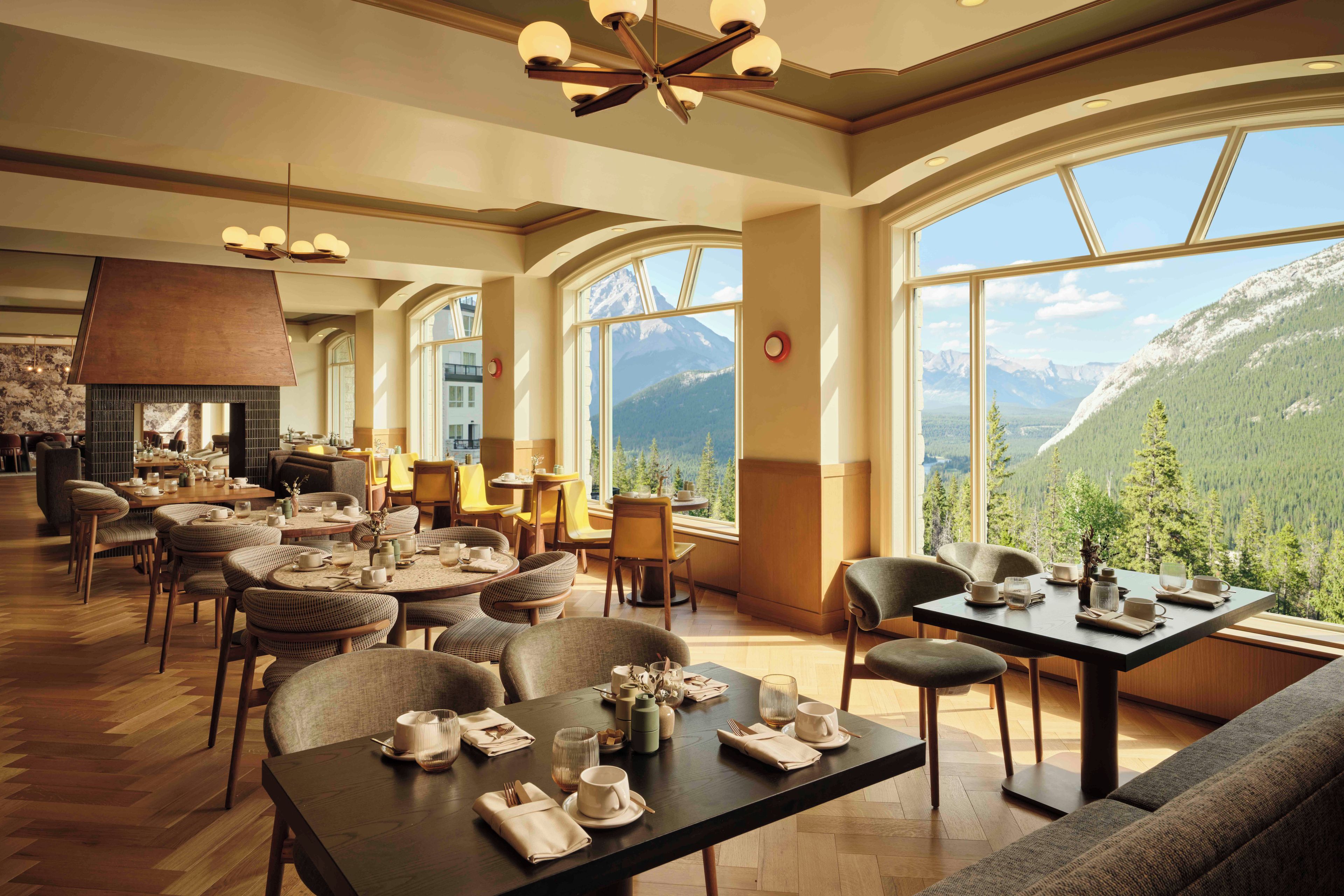 Restaurante com pé-direito alto, grandes janelas e vista para as montanhas.