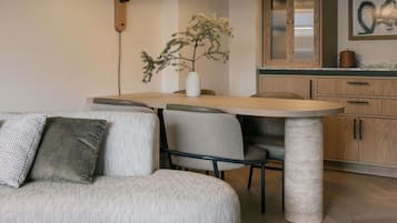 Uma sala de estar moderna com sofá, cadeiras, mesa de jantar e cozinha com armários e uma planta.