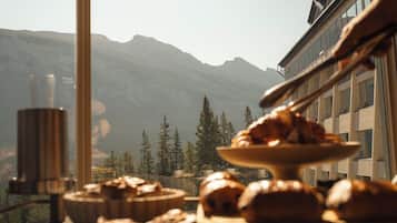 A table with pastries and a coffee cup, overlooking a mountainous landscape.