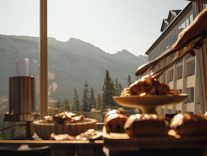 A table with pastries and a coffee cup, overlooking a mountainous landscape. - Rimrock Banff, Emblems Collection (Banff)