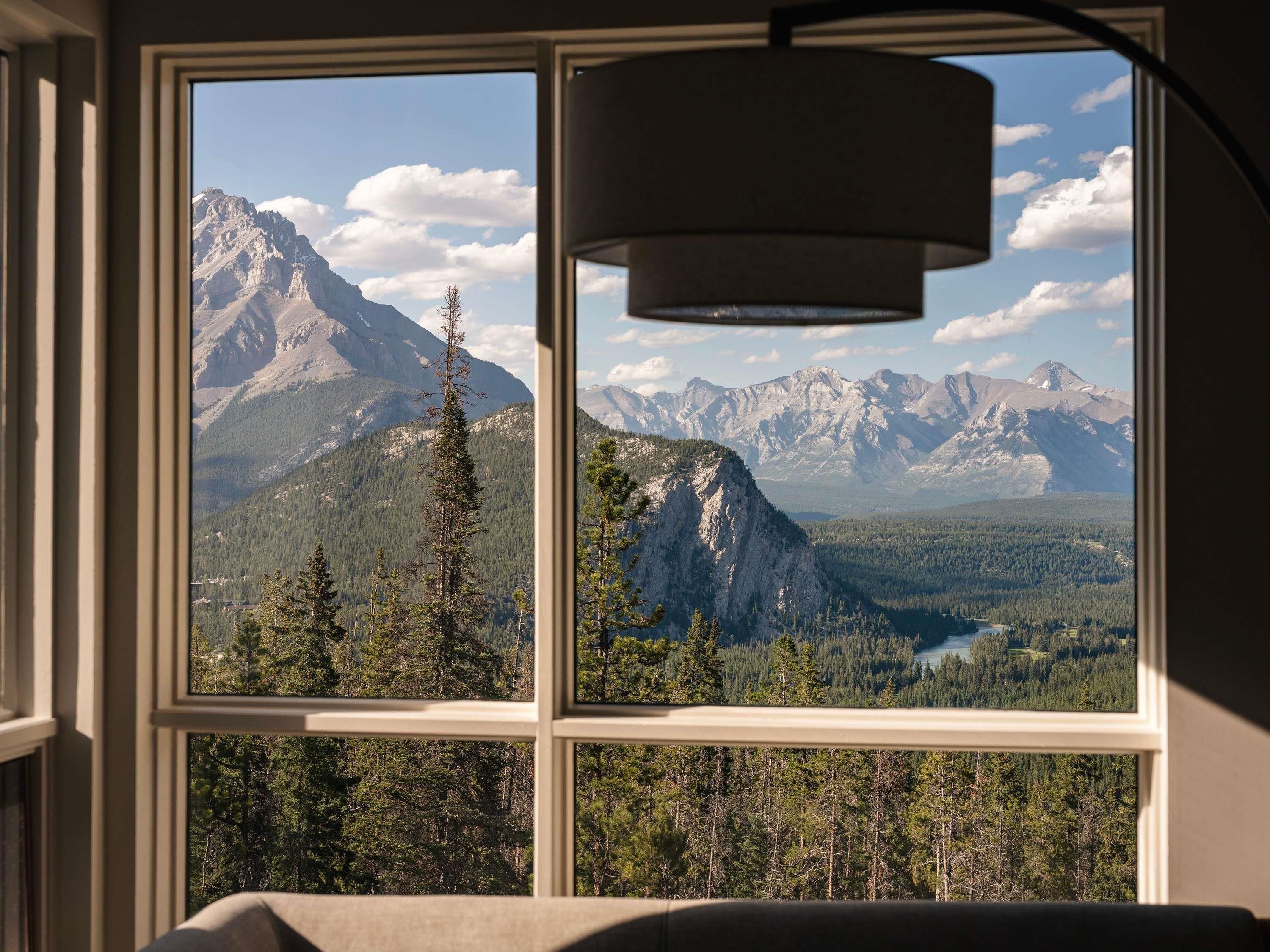 A room with a large window offering a mountain view.