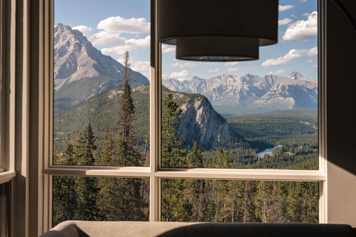 A room with a large window offering a mountain view.