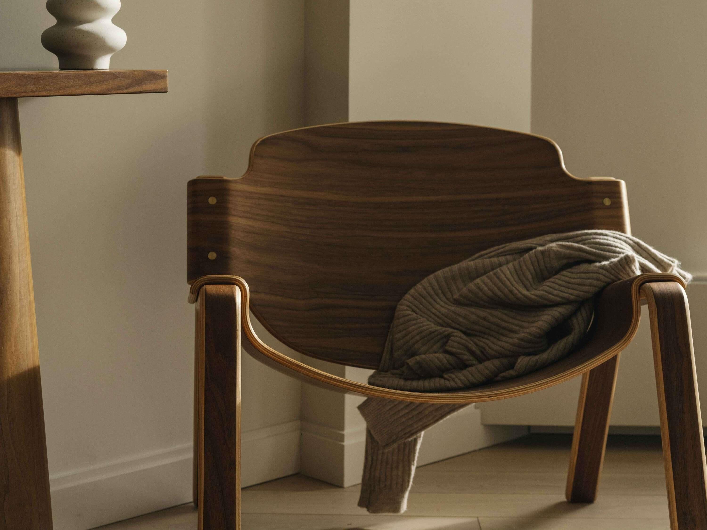 Een houten stoel met kussen, geplaatst naast een houten tafel met decoratief object.